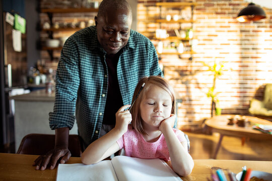 Senior man helping bored child with homework at home