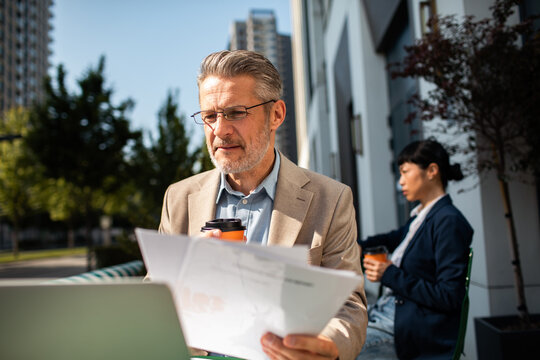 Senior businessman reviewing documents at outdoor cafe