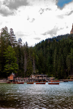 View of Pragser Wildsee with wooden rowing boats and a boathouse on stilts surrounded by a dense pine forest in Prags, Trentino-Alto Adige, Italy.