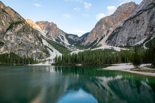 View of Pragser Wildsee with calm emerald waters reflecting the surrounding steep rocky peaks and dense pine forests Prags, Trentino-Alto Adige, Italy.