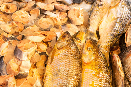 Close-up of whole bocachico fish and slices of salted and dried fish displayed for sale at a traditional market.