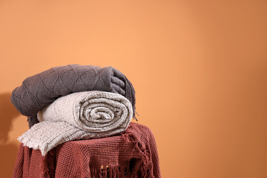 Chair with stack of soft blankets on orange background