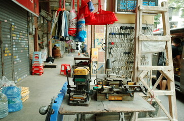 Fototapeta premium Street-side key-cutting shop with tools, ladder, and hanging goods in an urban alley in China