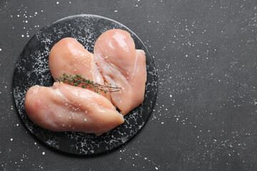 Board with raw chicken breast and thyme on black background © Pixel-Shot