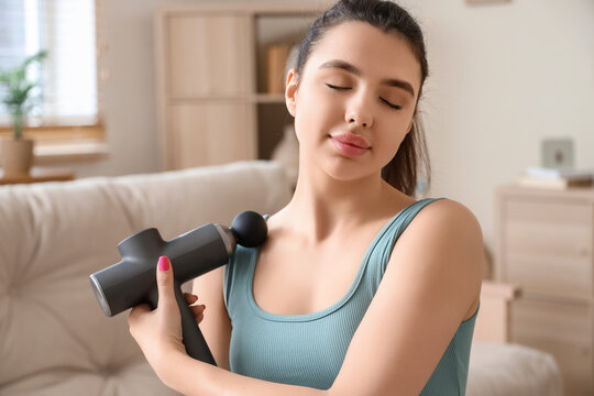 Sporty young woman with percussive massager at home, closeup