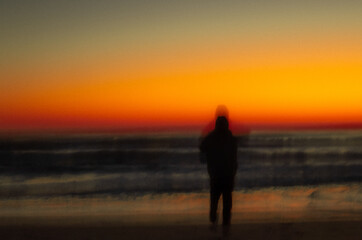 Fototapeta premium Blurry silhouette of person on the beach at sunrise