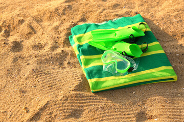 New swimming mask, flippers and towel on sand © Pixel-Shot