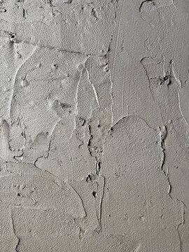 Close-up texture of a rough concrete wall with visible trowel marks, imperfections, and a raw, industrial loft style surface.
