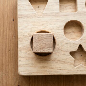 Square Wooden Block Pushed Into Round Hole on Sorting Board, Mismatch and Wrong Fit Concept