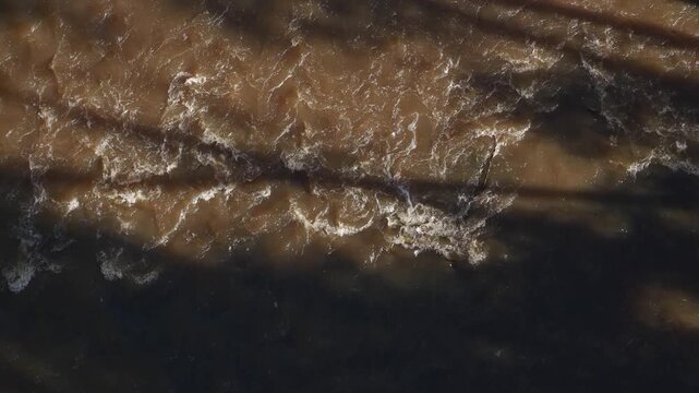 Top-down view of muddy river water flowing rapidly