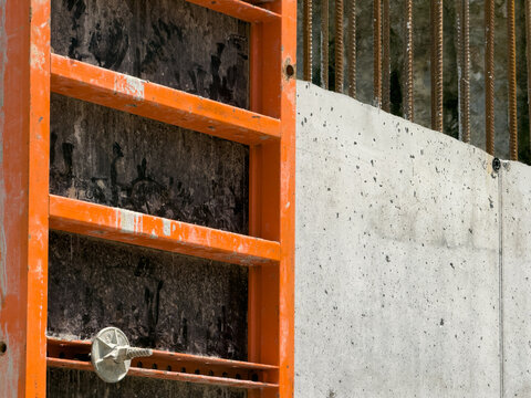 View of orange metal formwork and a textured concrete wall with vertical rebar at a construction site in Sariyer, Istanbul, Turkey.