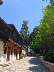 Fototapeta premium Peaceful historical stone-paved alley sloping upwards lined with traditional wooden houses and green trees