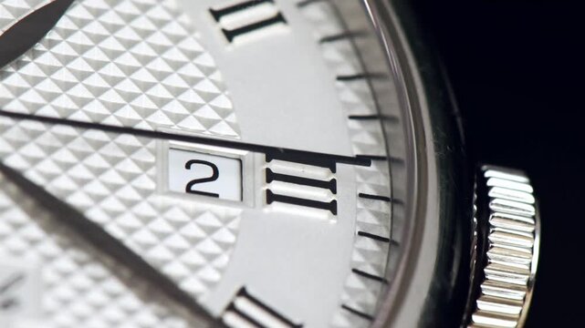 Macro closeup of elegant silver luxury wristwatch dial with moving watch hands.
