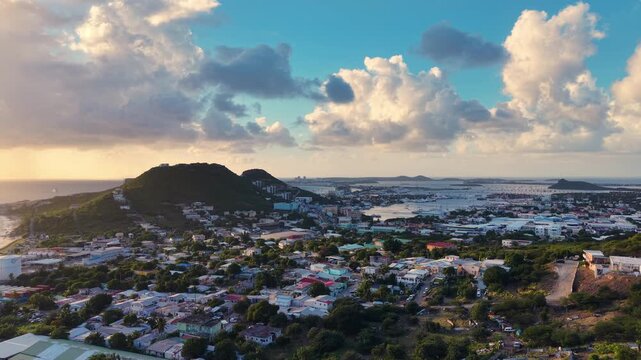 Aerial view of Cole Bay town and hills on the Dutch side of Sint Maarten island. Panoramic coastal landscape of the Caribbean destination under a cloudy sky. 
