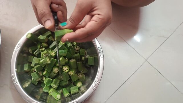 Cutting Fresh Green Okra Lady Finger Vegetables with Knife into a Bowl 
