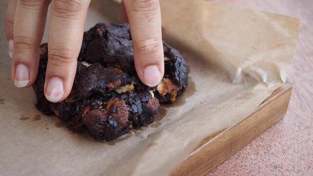 Enjoying a rich chocolate cookie on a wooden plate