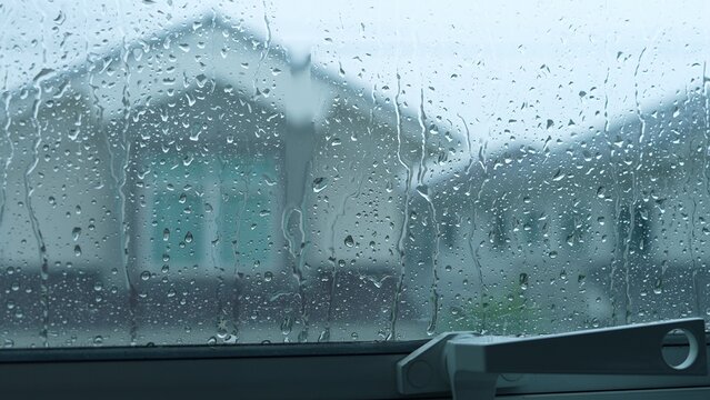 Raindrops streak down the glass, but the sealed window keeps the storm outside, reflecting on energy efficiency, climate adaptation, storm resilience, and the importance of secure housing.
