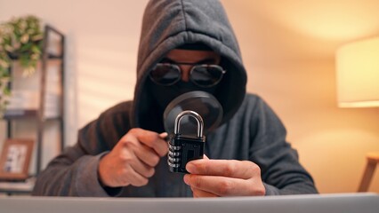 A hacker’s careful scrutiny of a lock with a magnifying glass stands for password cracking, digital infiltration, security loopholes, identity theft, and the challenge of online safety.  © Punyawee