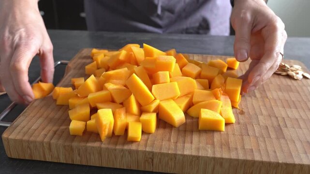A woman&rsquo;s hands sort through the chopped pumpkin. Planning the meal.