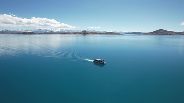 Boat Sailing on Yamdrok Lake with Snowy Mountains in Distance, Tibet