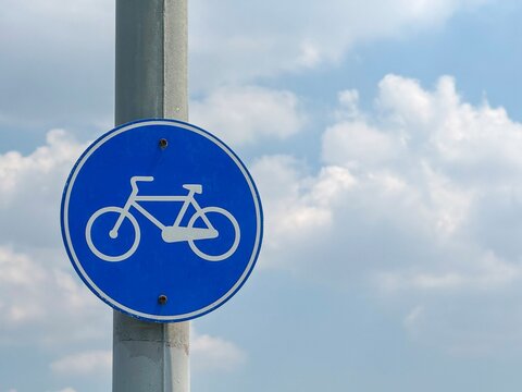 View of a blue circular bicycle path sign mounted on a metal pole against a cloudy blue sky Avcilar, Istanbul, Turkiye.