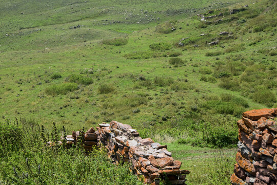 View of ancient stone walls on a lush green hillside with grassy slopes and scattered bushes in Avcilar, Istanbul, Turkiye.
