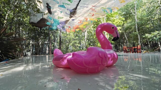 Pink flamingo pool float in luxury Tulum jungle villa swimming pool. Video of boutique hotel resort with traditional Mexican papel picado flags, Mexico.