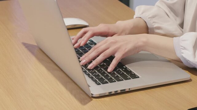 Close-up of woman's hands typing on laptop keyboard