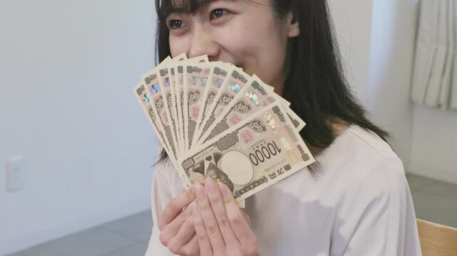 Asian woman smiling while holding ten 10000 yen banknotes