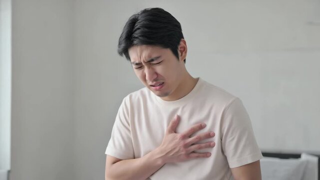 Young asian man touching his chest and feeling pain in heart. Healthcare and medicine