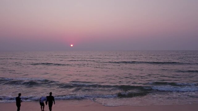 Pan view of people enjoying beach sunset with waves and relaxing coastal atmosphere
