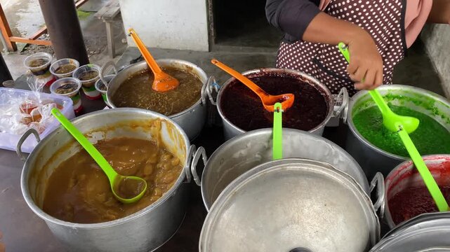 A vendor selling a variety of traditional Javanese jenang porridge. Jenang is typically made from rice flour with a sweet and savory flavor, and is served with melted palm sugar syrup.