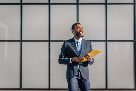 Smiling businessman holding folder looking confidently forward