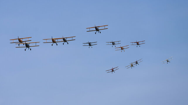 View of a formation of vintage biplanes flying across a clear blue sky during an air show La Ferte-Alais, Ile-de-France, France.