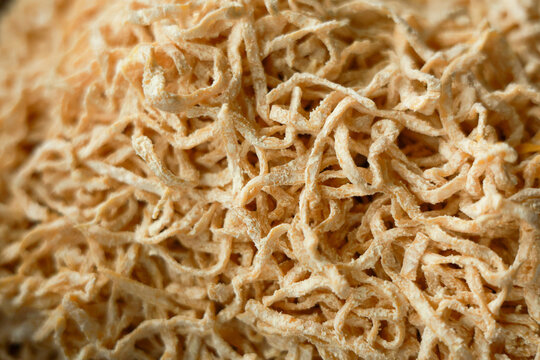Close up view of dried shredded food snack showing complex texture background. Inviting pile of savory chewy stringy seafood appetizer ready for eating