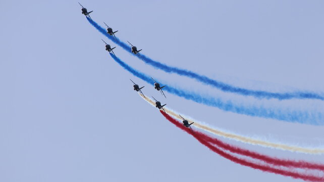 View of Patrouille de France aerobatic team jets flying in formation with blue, white, and red smoke trails against a clear sky La Ferte-Alais, Ile-de-France, France.