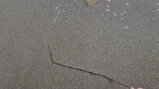 Sand drawing boat hand draws a simple boat sketch on a sandy beach as the tide comes in to erase the artwork
