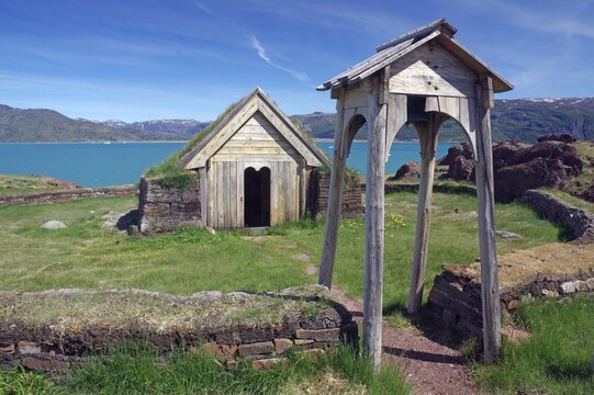 Replica of the first Christian church in Greenland, small wooden building behind stone wall, fjord and mountains behind, Bratthild, Qassiarsuk, Narsaq, Greenland, Denmark
