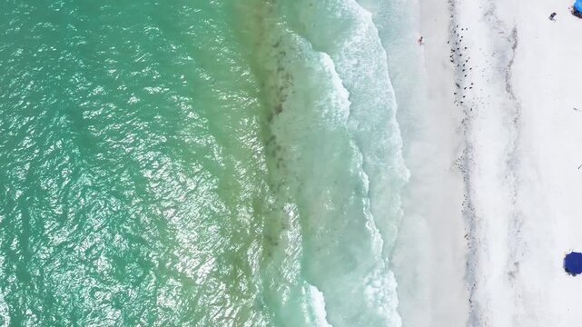 Gentle waves meeting the white sandy beach. The emerald ocean contrasts with the bright shoreline. Suitable for travel marketing or environmental documentaries.