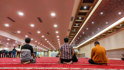 Obraz premium Men praying on a red carpet in a mosque