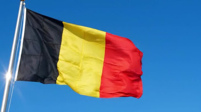 The national flag of belgium waving against a clear blue sky