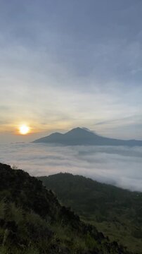 Trunyan and Abang Hills seen afar from Mount Batur in Kintamani, Bali, during golden sunrise with blue sky and scattered clouds in the morning. Concept of mountain hiking, adventure, and tourism