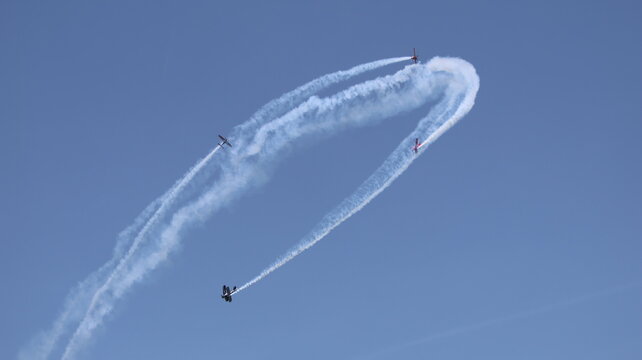 View of aerobatic planes performing maneuvers with white smoke trails against a clear blue sky La Ferte-Alais, Ile-de-France, France.