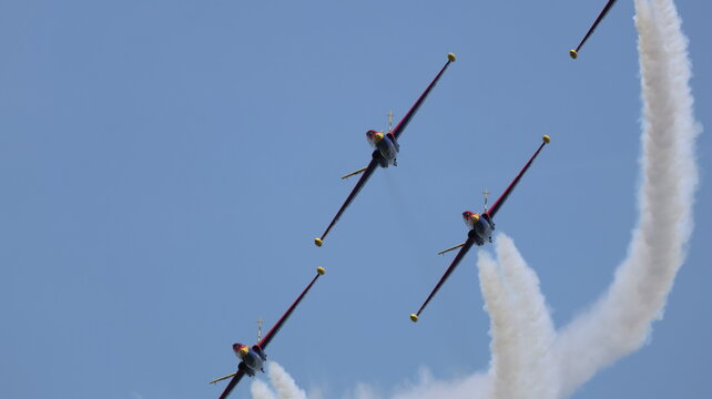 View of four Fouga Magister aerobatic jets performing a formation flight with white smoke trails against a clear blue sky at the airshow in La Ferte-Alais, Ile-de-France, France.