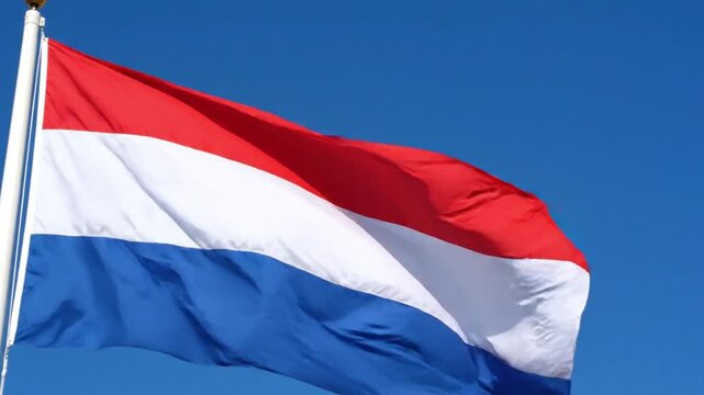 The national flag of the netherlands waving against a clear blue sky