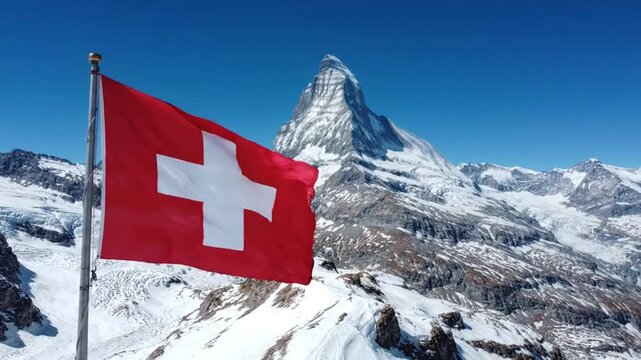 Swiss flag waving in front of the matterhorn mountain in the swiss alps