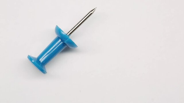 Office supplies, blue pushpin paperclip on white background rotating