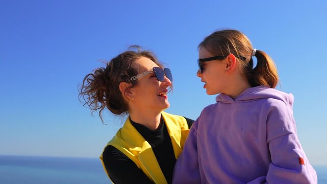 Mother daughter kiss happy woman and child share a loving moment wearing sunglasses at the sunny seaside