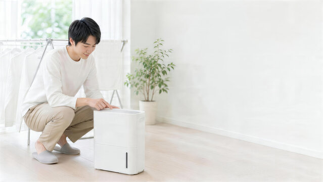 雨の日のリビングで除湿機を操作する男性の湿気対策