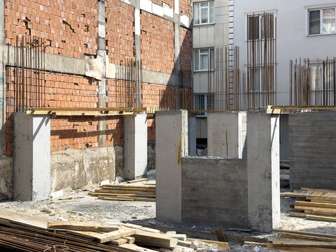 View of concrete pillars and steel rebar at an urban construction site with brick walls and residential buildings Sariyer, Istanbul, Turkiye.
